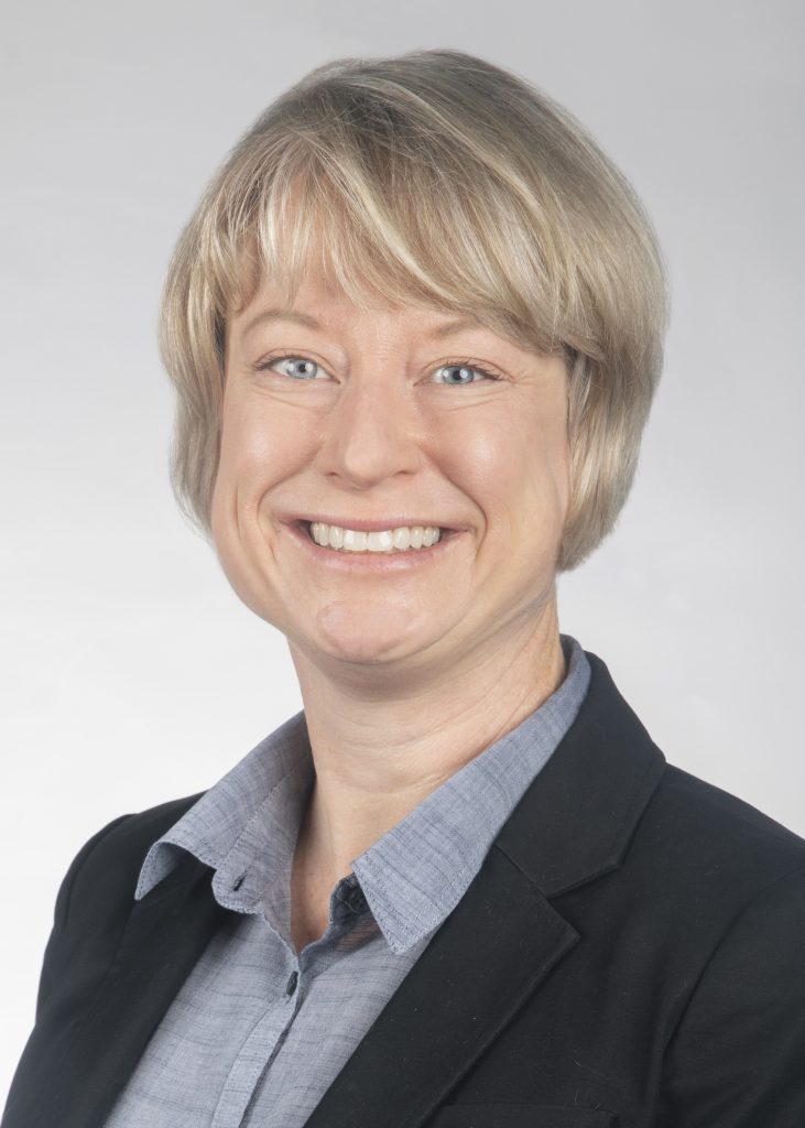 Darcy Holtgrave smiling in a black blazer with gray button down underneath.