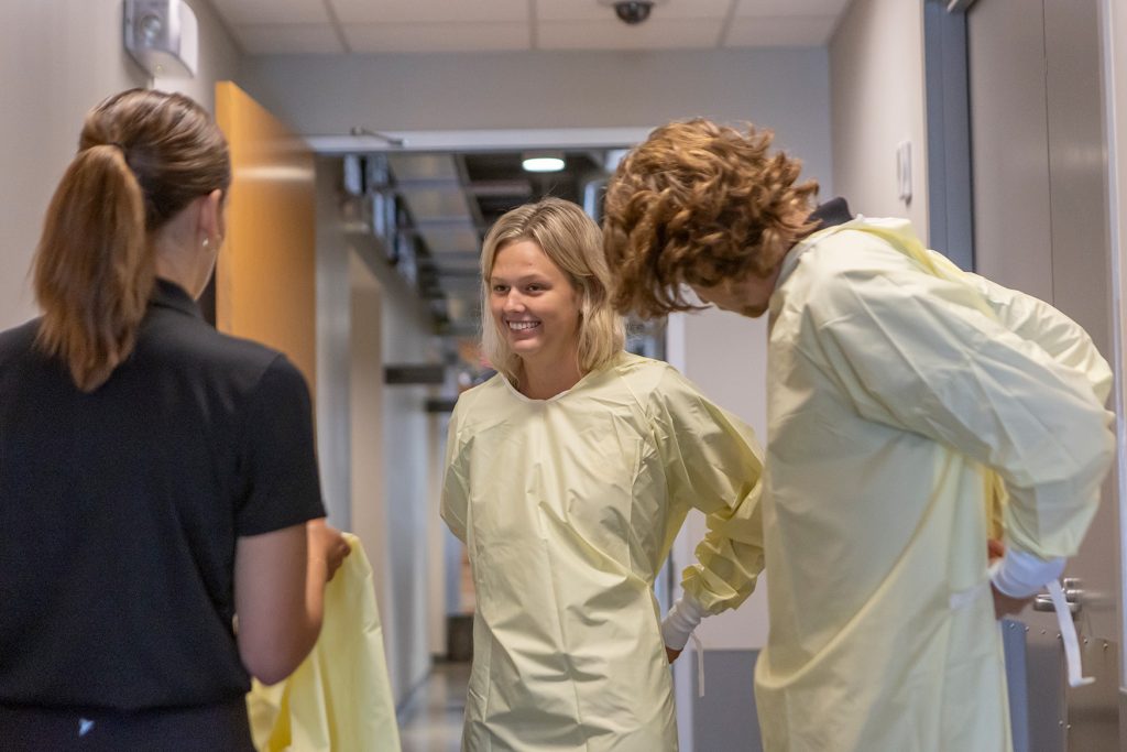 Three individuals talking while putting on medical robes.